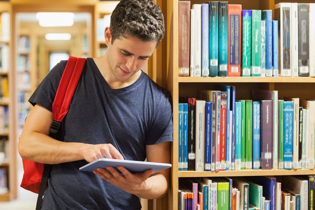 homem encostado em estante lendo livro sobre finanças