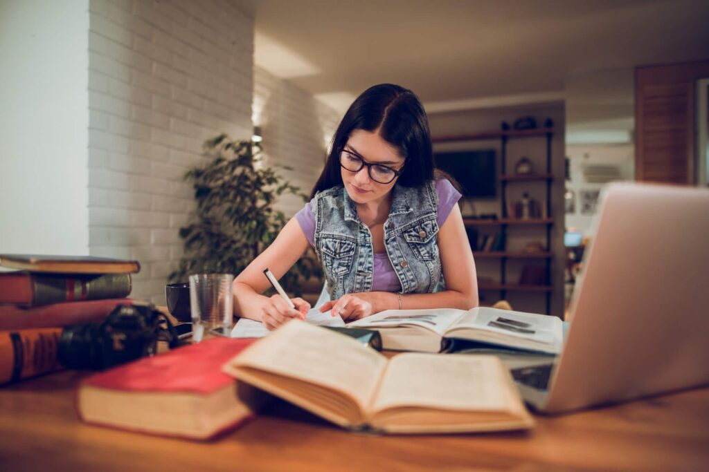 mulher sentada a uma mesa com livros abertos estudando sobre finanças