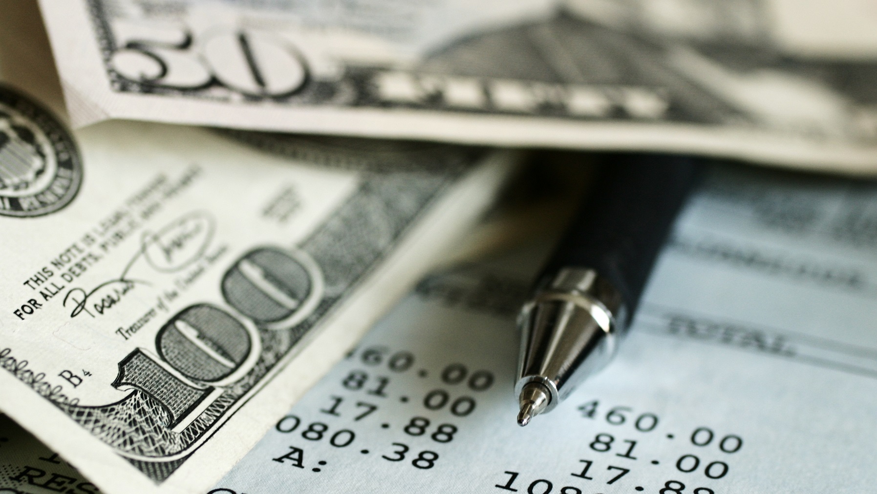 imagem com notas de dinheiro e uma caneta ao meio