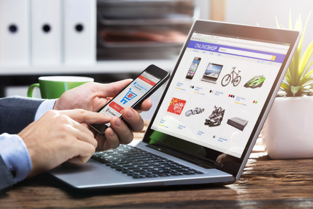 imagem de notebook aberte com site ecommerce e homem com celular na mão navegando no site