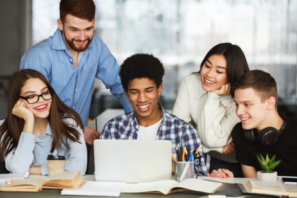 imagem-com-pessoas-ao-redor-de-um-notebook-vendo-vagas-de-trainee-e-de-estagio
