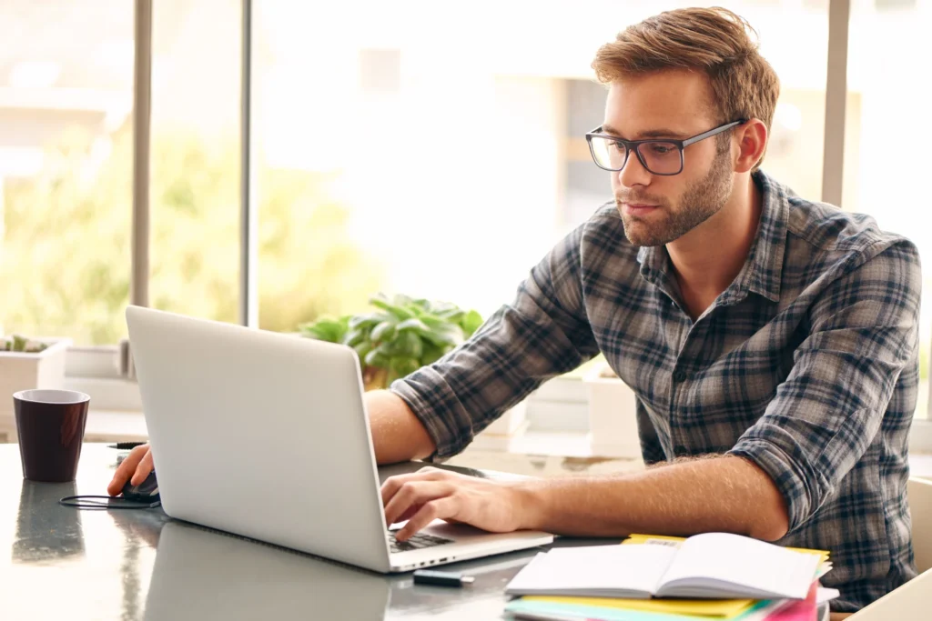 imagem de homem sentado mexendo no notebook respondendo uma pesquisa remunerada
