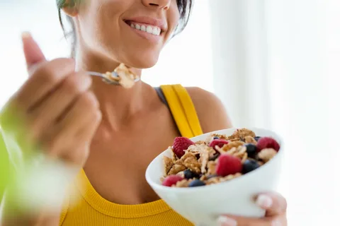 mulher comendo um cereais com frutas selecionadas para o bem estar